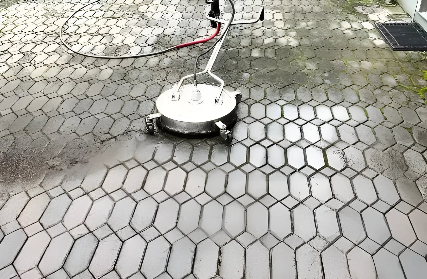 Surface cleaner mid-job on paver driveway — half cleaned, half still gray